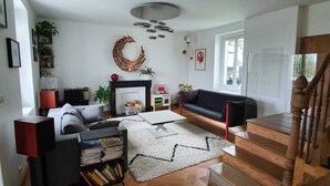 Un salon moderne avec une cheminée, un canapé noir, une table basse et un escalier menant à un autre niveau.