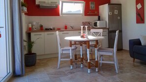 Une cuisine compacte comprenant un coin repas, un réfrigérateur et une fenêtre.