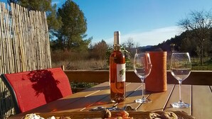 Une table en bois, dressée avec une bouteille de vin, des verres et une variété de collations et de sauces.