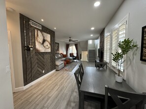 A modern kitchen with a herringbone wood floor, a dining area with a dark wood table and chairs, and a living area with a sofa and a large wall art piece. - Quiet, Comfortable, & Convenient North Phoenix Condo! (Phoenix)