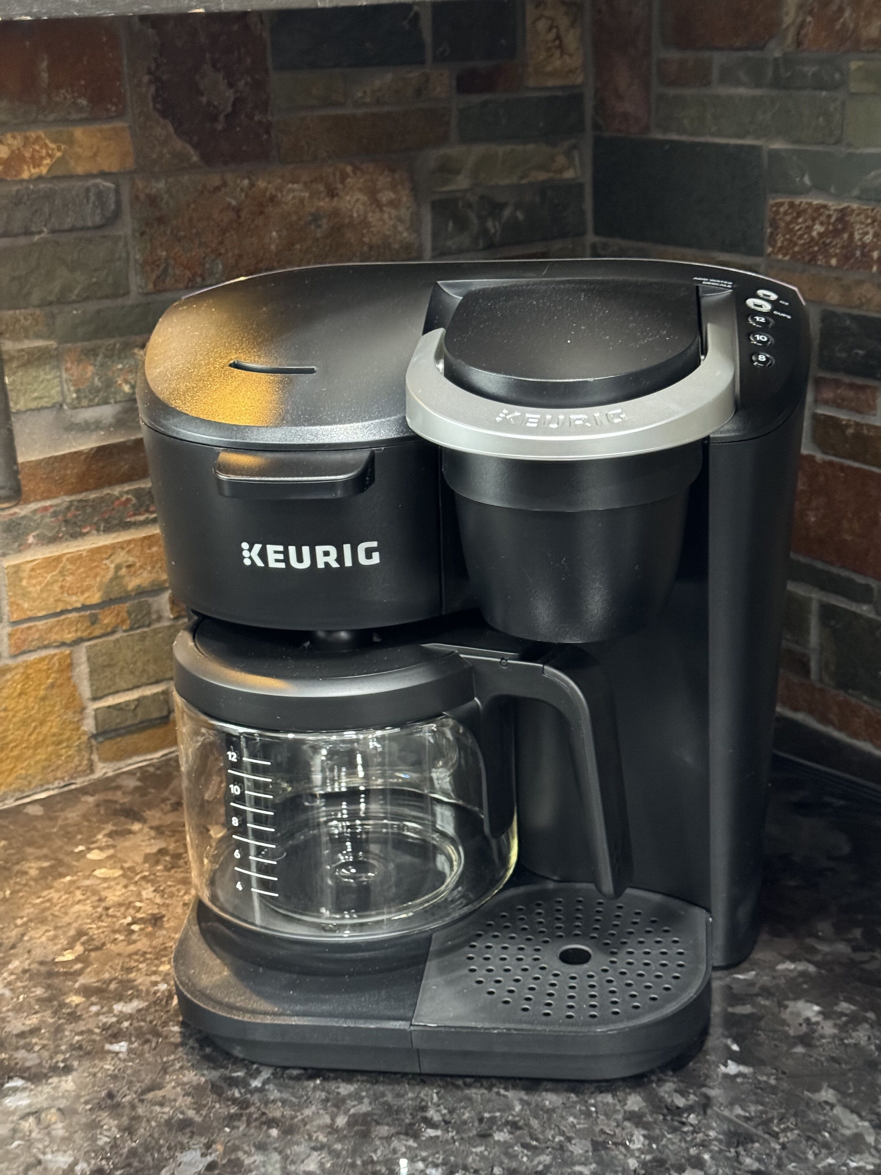 A Keurig coffee maker with a glass carafe and a drip tray, placed on a granite countertop.