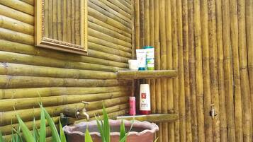 Un baño con pared de bambú, un espejo, un lavabo y artículos de aseo.