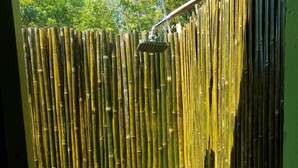 A bamboo shower enclosure with a shelf holding toiletries. - The Beachaven Chalets Kota Belud (Kota Belud)