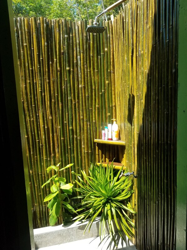 A bamboo shower enclosure with a shelf holding toiletries.
