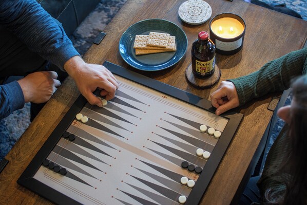 A board game on a wooden table with a candle and snacks nearby.