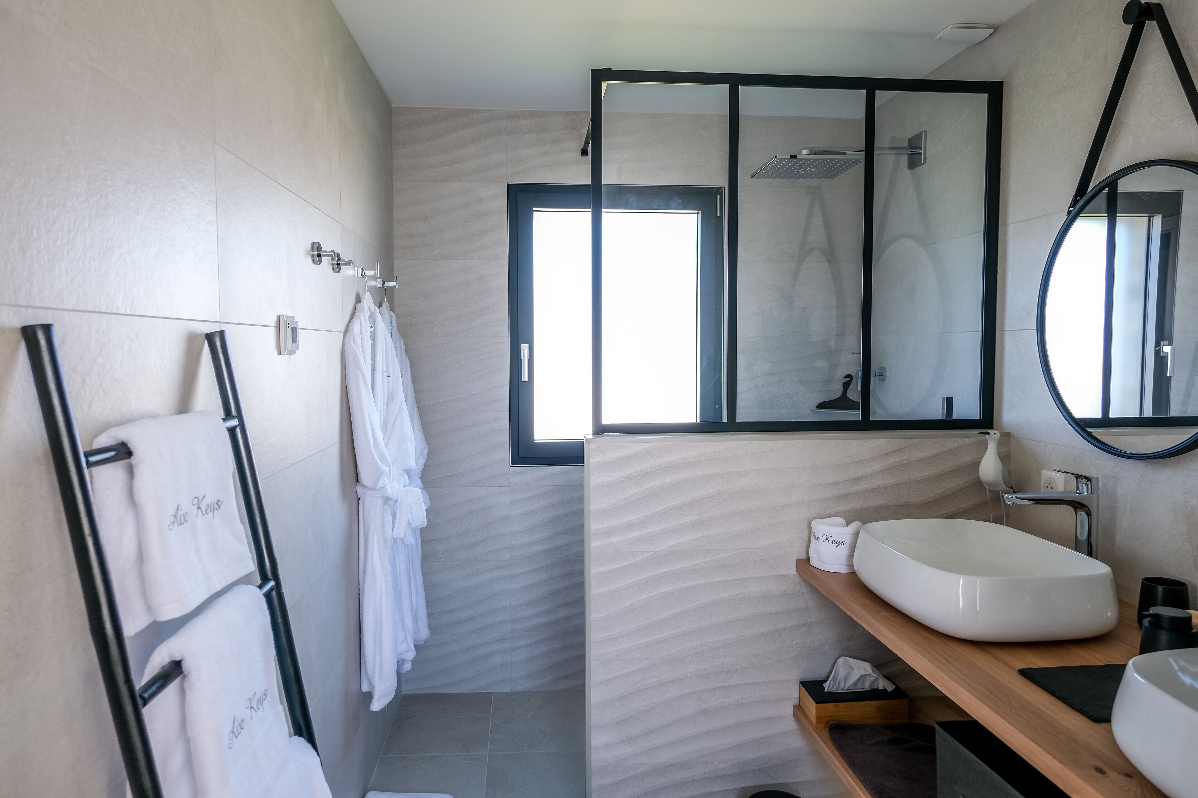 Un baño moderno con un espejo grande, un lavamanos blanco y un toallero con toallas.