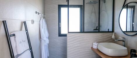 Un baño moderno con un espejo grande, un lavamanos blanco y un toallero con toallas.