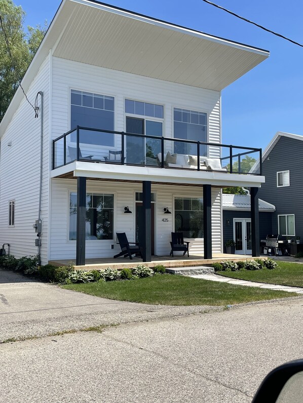 A two-story house with a balcony, a covered porch, and a grill area. - 180 degree lake view, luxury Port Stanley escape overlooking the beach! (Port Stanley)