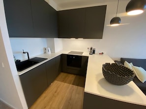 A modern kitchen with dark cabinetry, a white countertop, and a built-in oven.