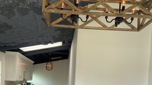 Een ruime keuken met witte kasten, een centraal kookeiland en een hangende lamp.