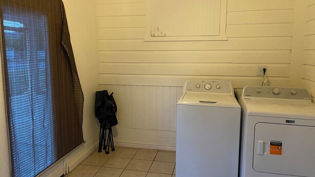 Een wasserette met twee wasmachines, een radiator en een raam met zonwering.