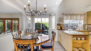 A dining area with a round table, chairs, and a chandelier. There is a kitchen with a sink and cabinets. - Beautiful Home in Northwest Napa

 (Napa)