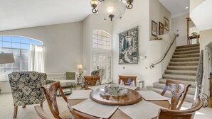 A spacious living room with a round wooden table, several chairs, a sofa, and a staircase leading to an upper floor. - Beautiful Home in Northwest Napa

 (Napa)