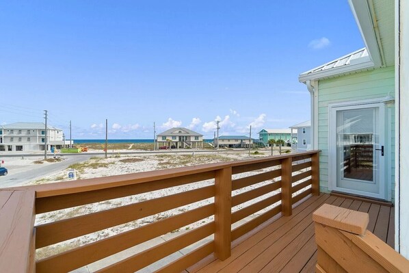 A wooden deck with a view of the beach and ocean.