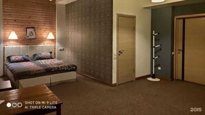 Ein Schlafzimmer mit Bett, Nachttischlampen, einer Holzbalkendecke, strukturierter Tapete und einem Kleiderständer.