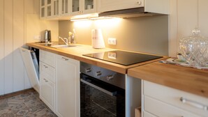 Una cocina con armarios blancos, un horno negro y una encimera de madera.