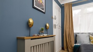 Een kamer met een blauwe wand, een houten receptiebalie, een witte deur en een raam met beige gordijnen.