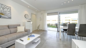 A modern living room with a sofa, coffee table, and dining area.
