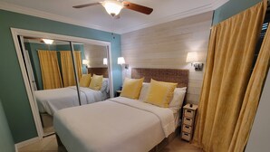 Un dormitorio con dos camas, un ventilador de techo y un espejo.