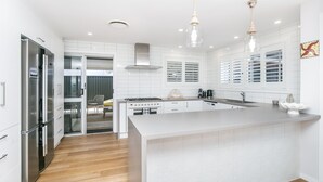 Een moderne keuken met witte kasten, een centraal eiland, roestvrijstalen apparatuur en hanglampen.