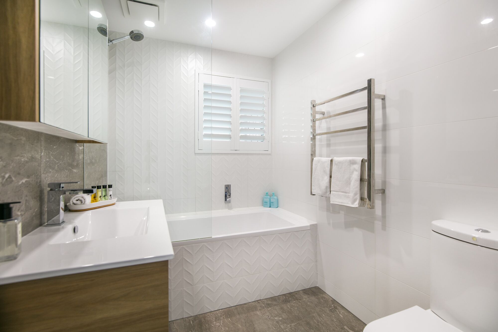 Un bagno moderno con una vasca, un lavabo con specchio e un water.