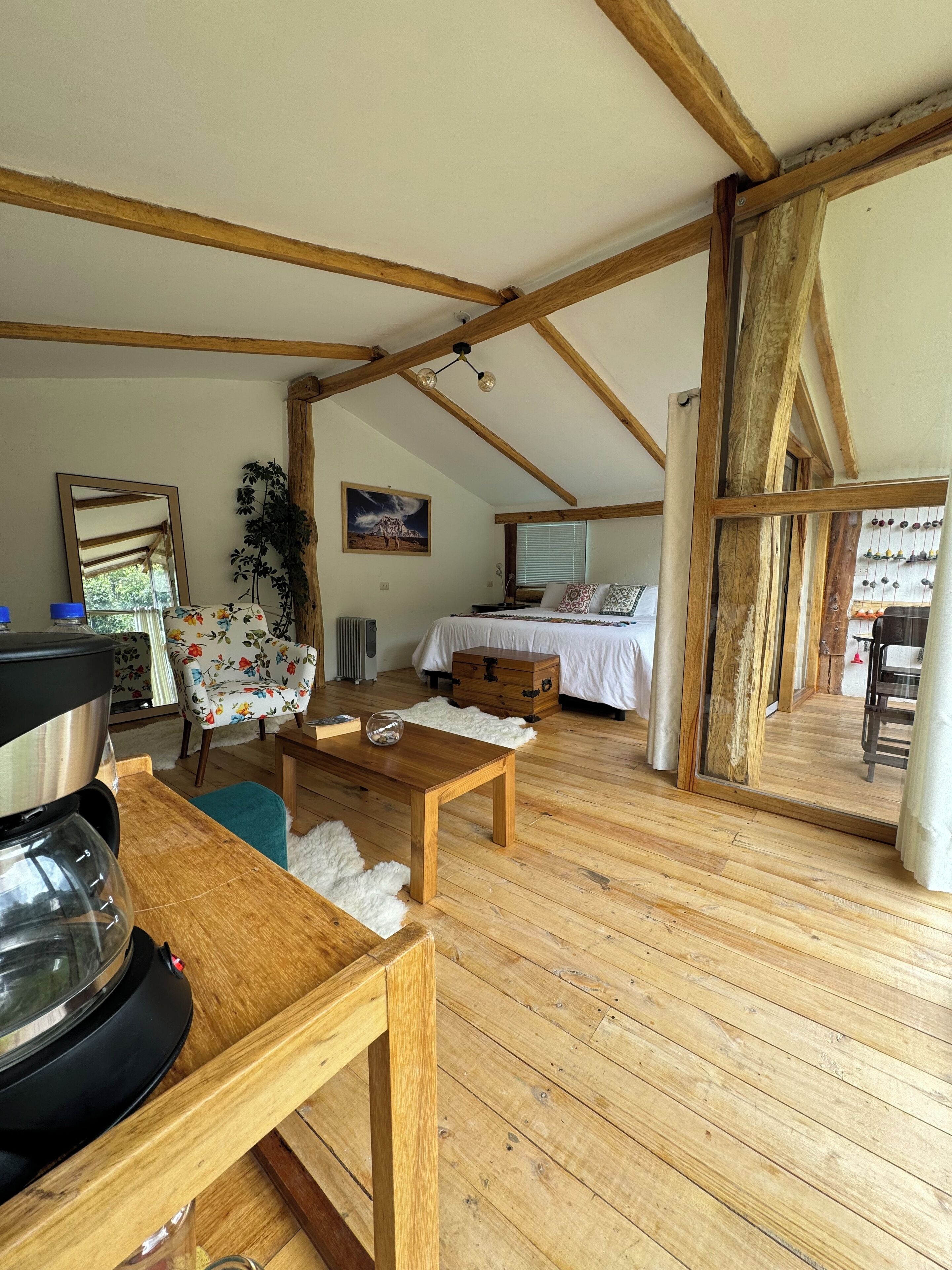 Una habitación acogedora con vigas de madera, una cama, una mesa y una silla.