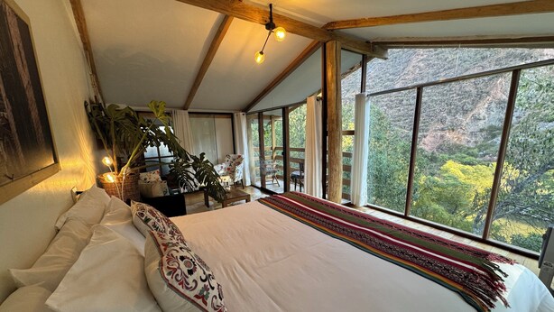 Un dormitorio espacioso con una cama grande, vistas al exterior y techo de madera.