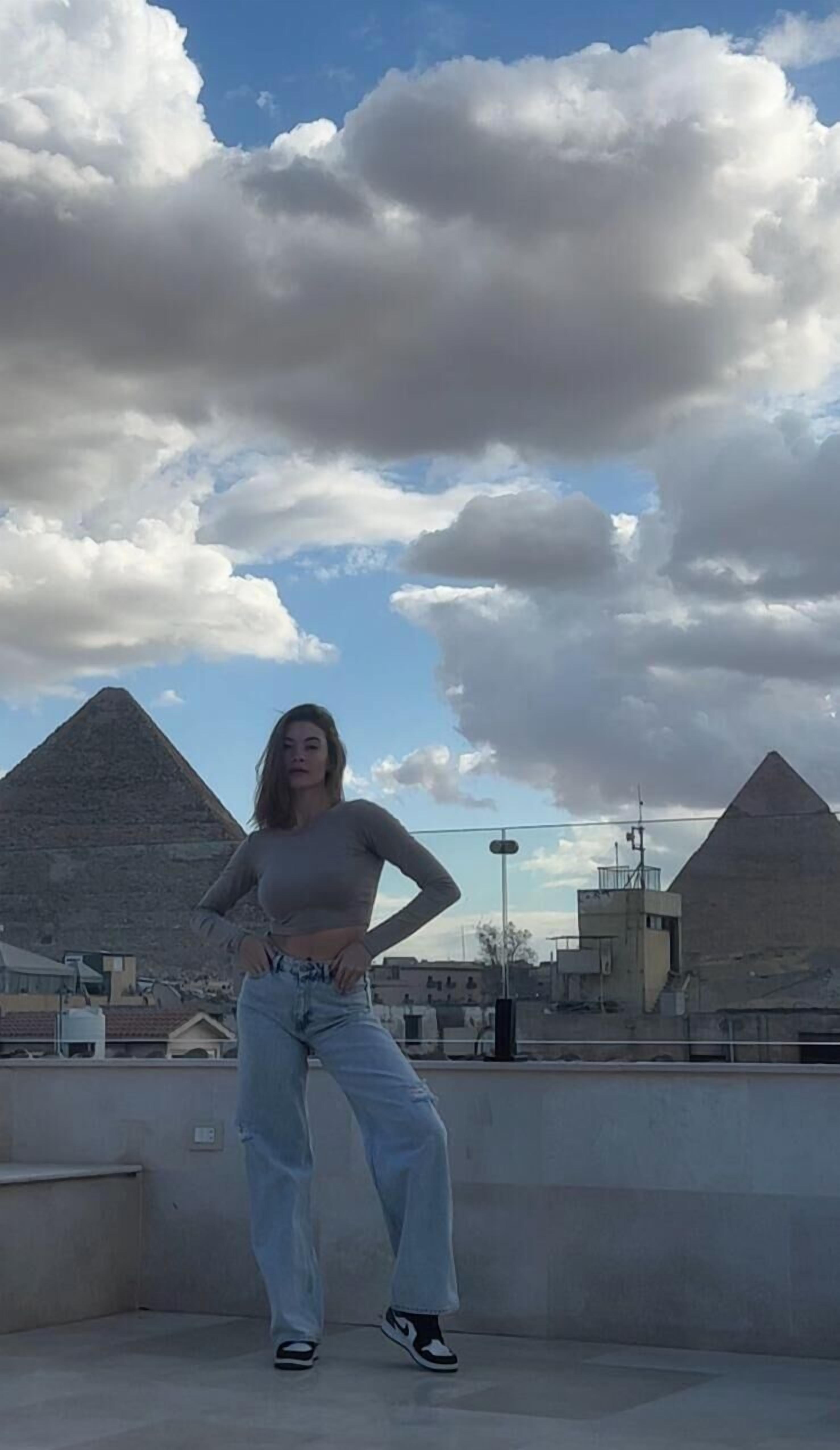 Una persona in piedi su un tetto con vista sulle piramidi sullo sfondo.