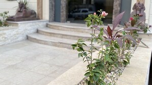 A stone planter with plants and a statue of a sphinx on a stone ledge. - Aziz Egypt Pyramids Hotel (Giza)