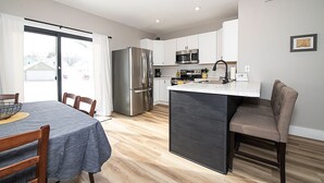 A modern kitchen with a central island, stainless steel appliances, and a dining area with a table and chairs. - Charming 3-bedroom, 2 bathroom house with outdoor space in Winona (Winona)