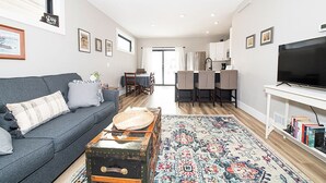 A modern living room with a sofa, a coffee table, a rug, and a television. - Charming 3-bedroom, 2 bathroom house with outdoor space in Winona (Winona)