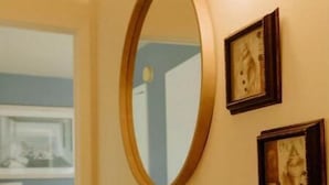 Een badkamer met een houten wastafelmeubel, een ronde spiegel en twee ingelijste foto's aan de muur.