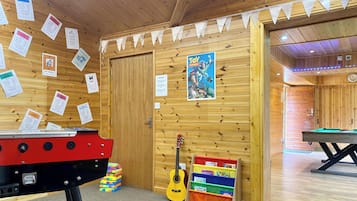 A wooden room with a pool table, a dartboard, and a guitar. There are signs on the wall and a poster of 'Toy Story'.