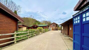 A row of wooden cabins with a concrete path, a blue police box, and a wooden fence.