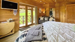 A wooden cabin with a bed, a sofa, a TV, and a desk. - 1 bedroom accommodation in Camerton, near Bath (Camerton, near Bath)