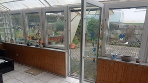 A conservatory with wooden walls and a tiled floor, featuring a glass door leading outside. - Gemütliche Erdgeschosswohnung mit Terrasse in Ortsrandlage in Waibstadt (Waibstadt)