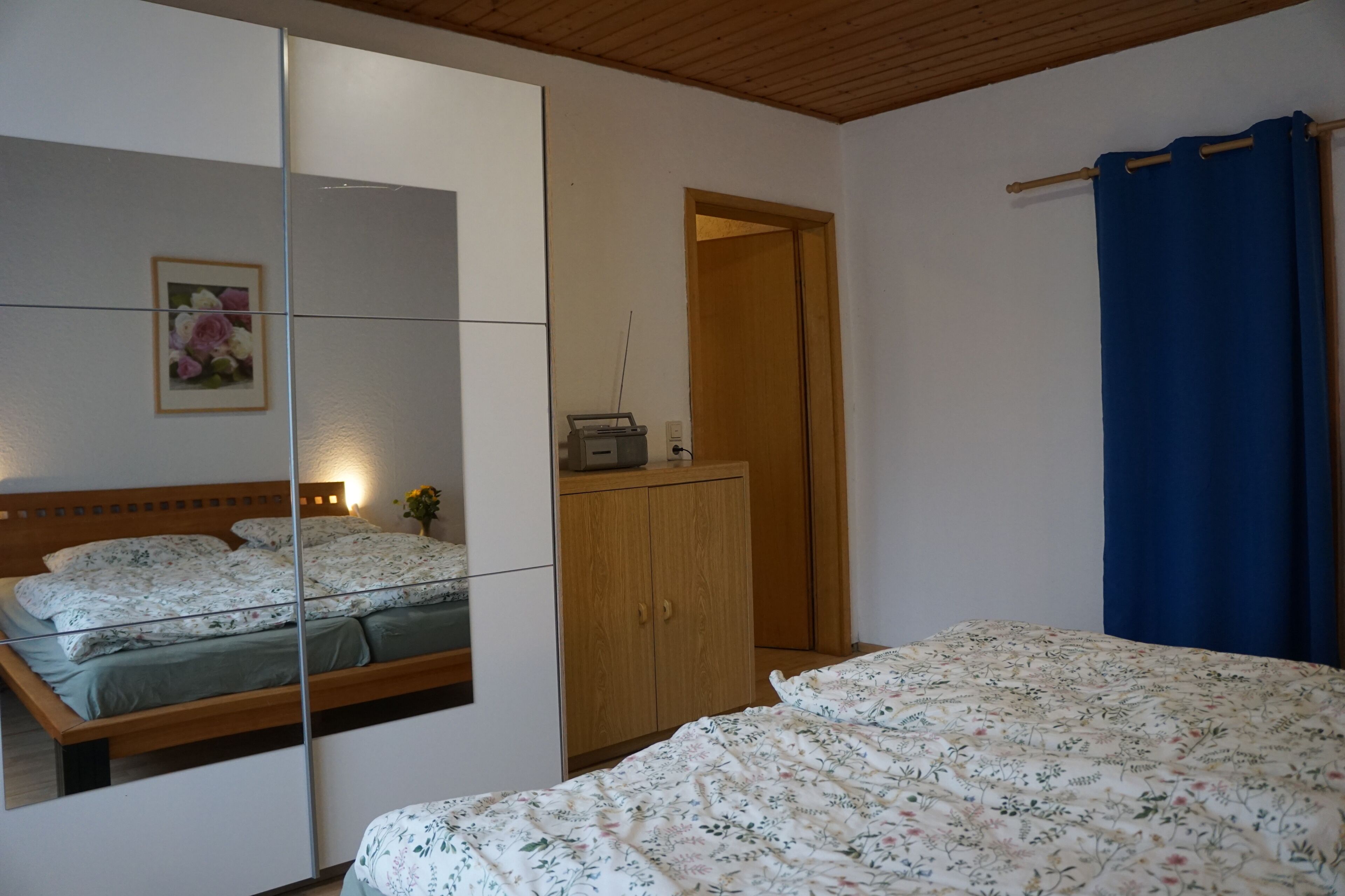 Une chambre à coucher avec un lit, une armoire, un miroir et une porte.
