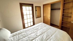 Un dormitorio con cama, armario y ventana con persianas.
