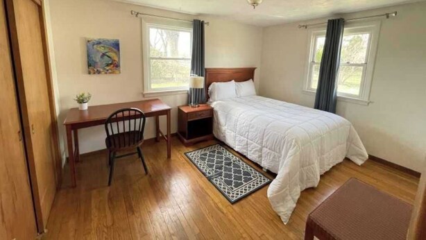 Un dormitorio con cama, escritorio, silla y una mesita con una planta.
