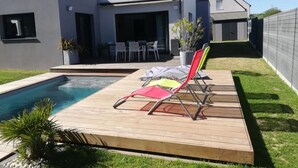 A modern house with a swimming pool, deck chairs, and a patio area. - Maison Moderne Avec Piscine Chauffée, à 1km de L'avenue de Gaulle à La Baule (Guérande)
