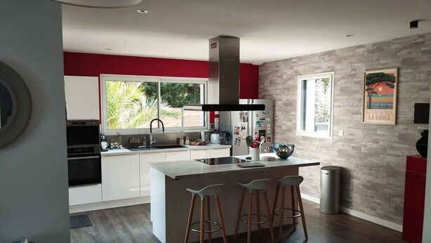 A modern kitchen with a central island, bar stools, and a large window. - Maison Moderne Avec Piscine Chauffée, à 1km de L'avenue de Gaulle à La Baule (Guérande)