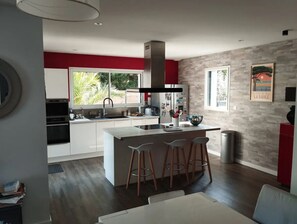Una cucina moderna con isola centrale, sgabelli da bar e un'ampia finestra.