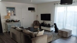 A modern living room with a sofa, coffee table, and a television. - Maison Moderne Avec Piscine Chauffée, à 1km de L'avenue de Gaulle à La Baule (Guérande)