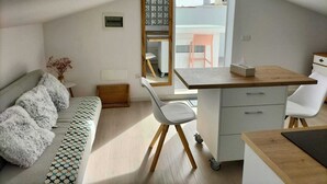 Ett kompakt och modernt rum med en säng på ett loft, ett litet skrivbord och en matplats.