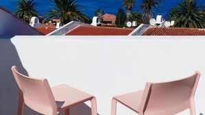 En terrass med två rosa stolar och utsikt över havet.