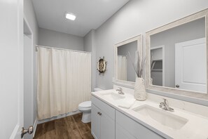 Features a sleek vanity with dual sinks and a large mirror.