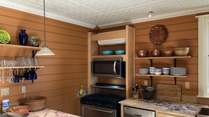 Une cuisine avec des meubles de rangement en bois, un four à micro-ondes, une cuisinière et un lave-vaisselle.