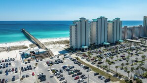 Un hotel de gran altura con varios pisos, estacionamiento y vista al mar.