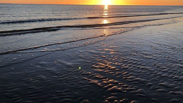 A beach at sunset with waves gently lapping onto the shore. - Gemütliche Ferienwohnung Mitten im Zentrum von Büsum (Büsum)