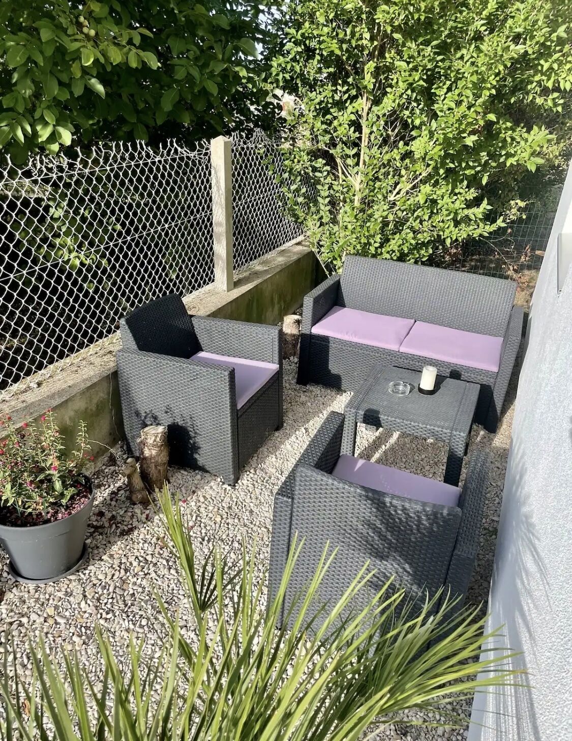 Un espace extérieur aménagé avec des meubles en osier et une clôture en treillis métallique.
